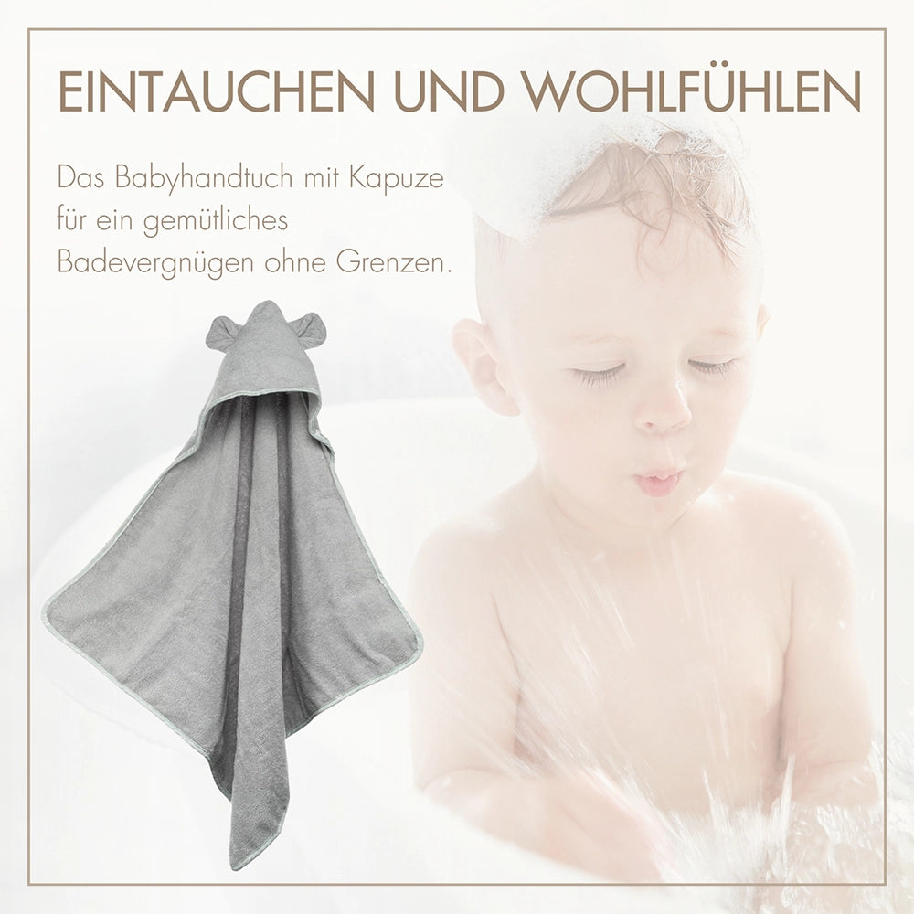 Zufriedenes Baby im grauen Kapuzenhandtuch von MOYO – perfekter Schutz vor Kälte nach dem Baden.