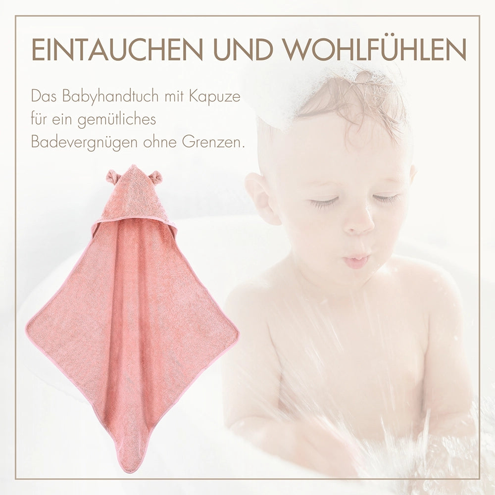 Glückliches Baby nach dem Baden, eingekuschelt in das rosafarbene MOYO Kapuzenhandtuch für sanftes Abtrocknen ohne Hautirritationen.