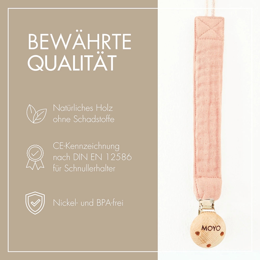 Nahaufnahme der MOYO Schnullerkette mit Holzclip und dem Schmusetuch in einer Geschenkverpackung mit Trockenblumen.