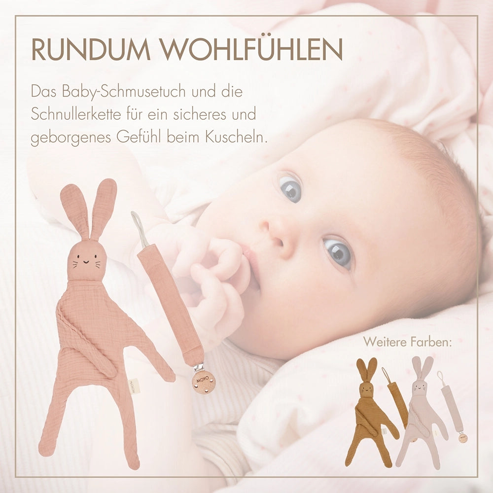 Ein Baby kuschelt mit dem MOYO Schmusetuch und nutzt die Schnullerkette – Wohlfühlmomente und Sicherheit für Neugeborene.