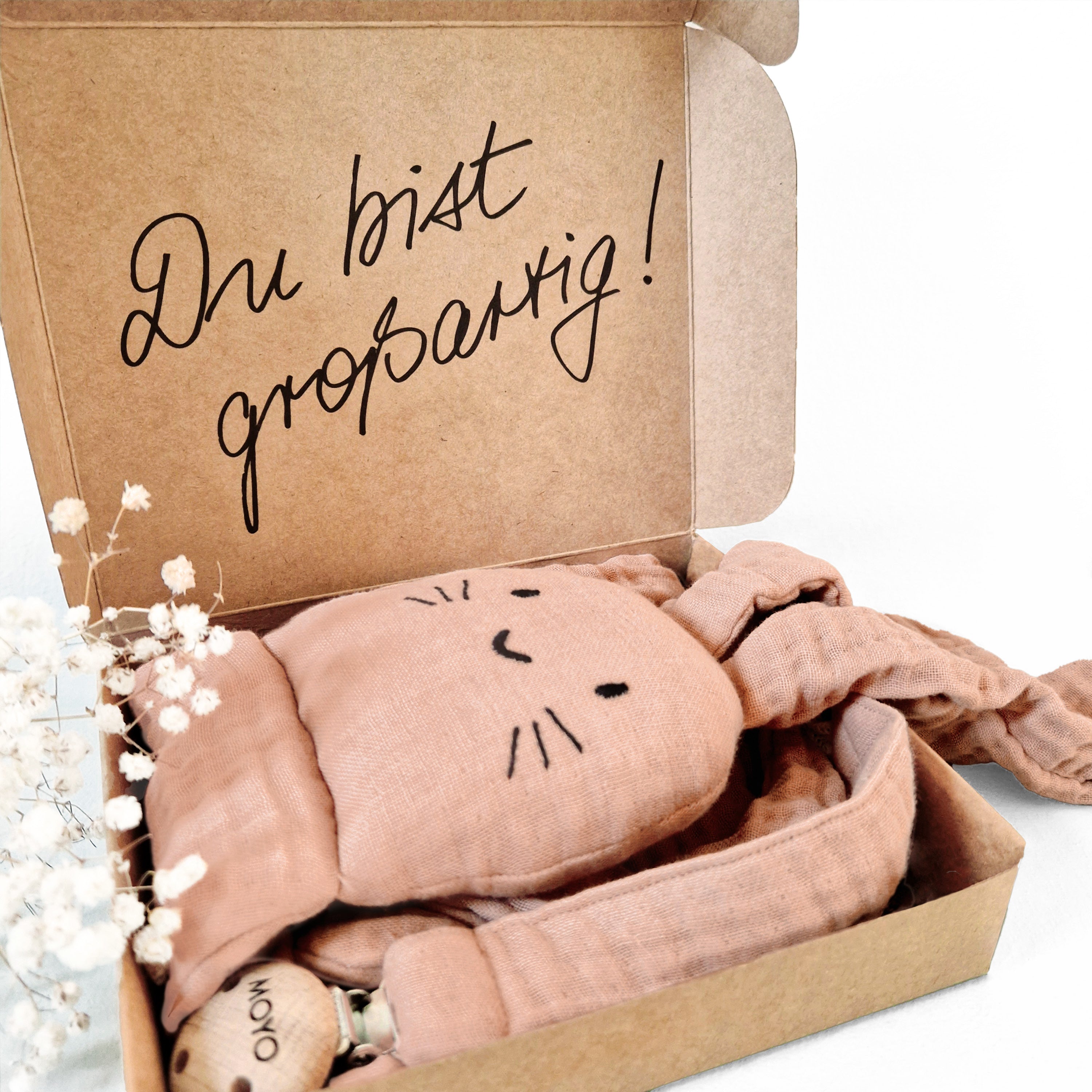 Geöffnete MOYO Geschenkbox mit dem Text „Du bist großartig“ und dem Kuschelhasen in Rosenholz als liebevolles Präsent.