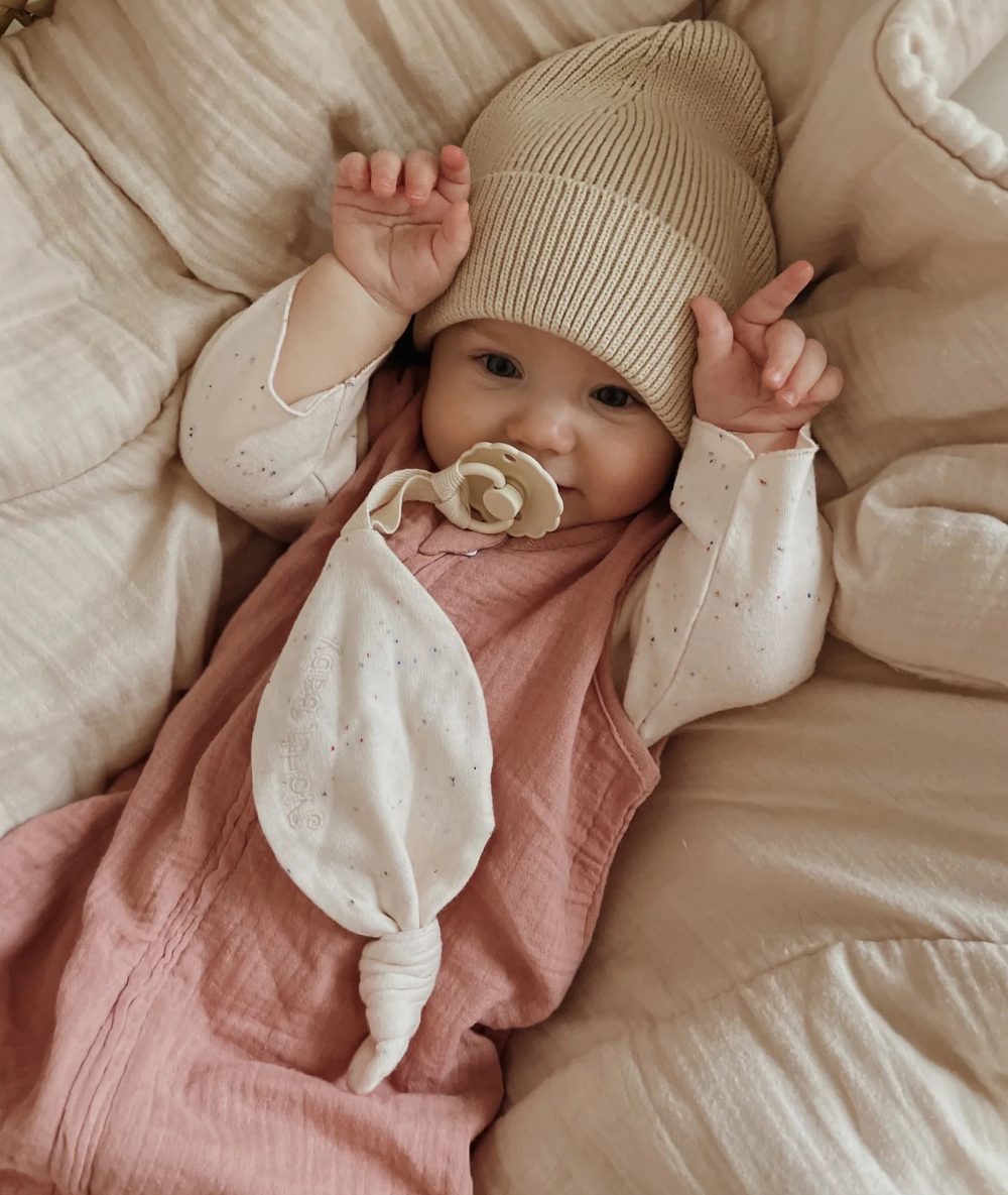 Ein Baby im gemütlichen Musselin-Sommerschlafsack und Mütze von Räuberella bereit für den erholsamen Schlaf bei idealer Temperatur.